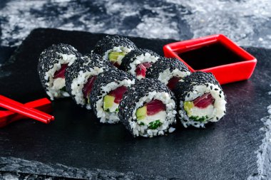 siyah susam ve ton balığı ile suşi rulo, soya ve Chopsticks ile siyah tepsi üzerinde suşi rulo