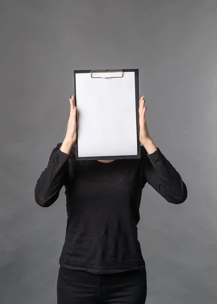 girl hides her face behind blank blank white sheet copy space for text