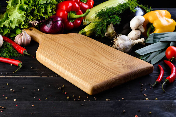 empty wooden board mockup and fresh vegetables on wooden black background