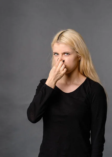 girl gesture smells bad Bad smelling concept. Studio shot of disgusted young European woman pinching her nose because of awful stink coming out from garbage or spoiled food. Negative human emotions