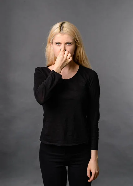 girl gesture smells bad Bad smelling concept. Studio shot of disgusted young European woman pinching her nose because of awful stink coming out from garbage or spoiled food. Negative human emotions