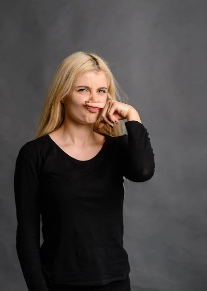 girl gesture smells bad Bad smelling concept. Studio shot of disgusted young European woman pinching her nose because of awful stink coming out from garbage or spoiled food. Negative human emotions