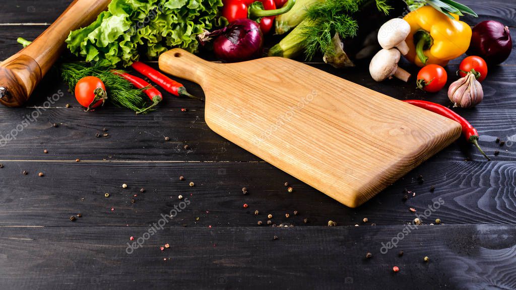 Empty wooden board mockup and fresh vegetables on wooden black background