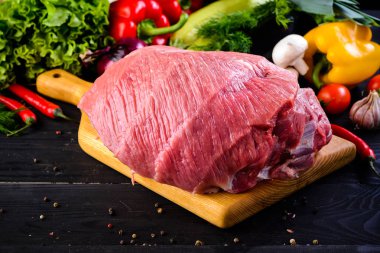 Çiğ domuz eti. Koyu arka plan üzerinde ahşap kesme tahtası üzerinde taze biftek bonfile. Sebze ve baharatlar ile kalça çiğ et