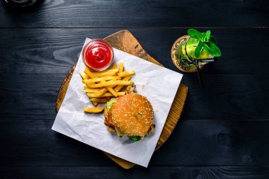 Barda siyah bir masada ızgara tavuk ve patates kızartması.