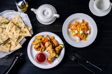 Kafe restoranındaki siyah bir masada kebap ve sos.