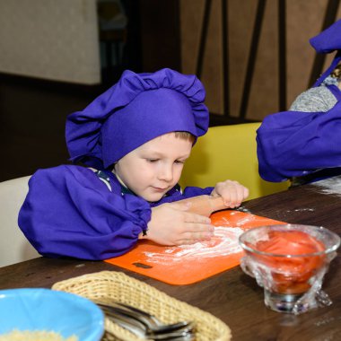 şirin ufaklikla chef şapka ayakta masada ekmek hamur yoğurma