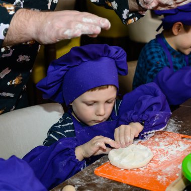 şirin ufaklikla chef şapka ayakta masada ekmek hamur yoğurma