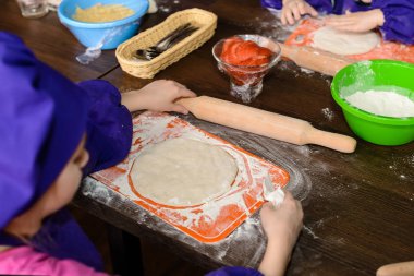 bir çocuğun elinde hamur, ahşap bir masa.