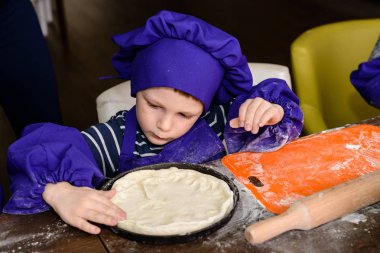 Çocuklar pizza yapar. İtalyan pizzası pişiren çocuklar için master class. Küçük çocuklar pizza pişirmeyi öğrenirler. Ev yapımı pizza hazırlayan çocuklar