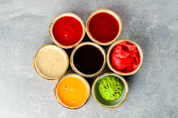 Различные вкусные соусы в мисках на сером фоне — стоковое фото