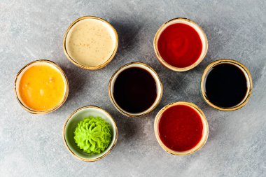 Kase gri arka plan üzerinde farklı lezzetli soslar