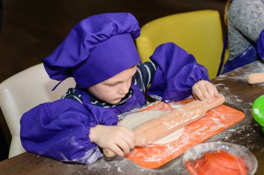 şirin ufaklikla chef şapka ayakta masada ekmek hamur yoğurma