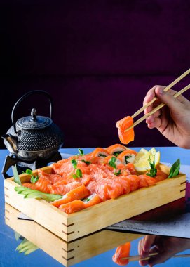 El kullanmak bambu sopa masada yemek için çiğ somon almak. iyi bir yaşam yaşam tarzı için ham sağlıklı yeme gıda