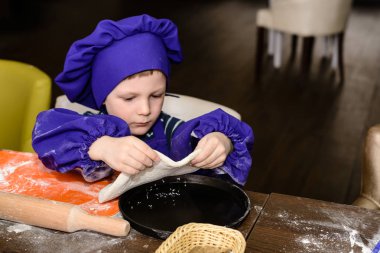 Çocuklar pizza yapar. İtalyan pizzası pişiren çocuklar için master class. Küçük çocuklar pizza pişirmeyi öğrenirler. Ev yapımı pizza hazırlayan çocuklar