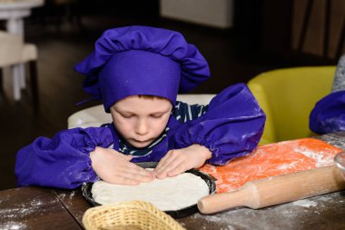 Çocuklar pizza yapar. İtalyan pizzası pişiren çocuklar için master class. Küçük çocuklar pizza pişirmeyi öğrenirler. Ev yapımı pizza hazırlayan çocuklar