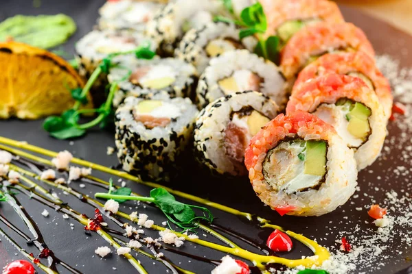 Beautiful looking sushi, sushi as work of art. Closeup sushi rolls top view, rice, cavair, flower garnish and wasabi. — Zdjęcie stockowe