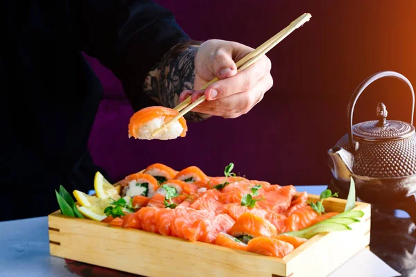 Hand use bamboo stick pick raw salmon for eating on table. raw healthy eating food for good living lifestyle