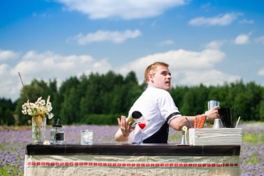 catering bar hizmeti, barmen gösterisi. Yakışıklı barmen bar sayacı yakınında kokteyller hazırlanıyor, açık havada