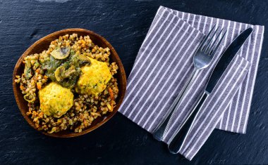 Ahşap masada mavi tabakta karabuğday lapalı tavuk pirzolası..