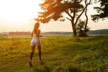 Koşucu atlet bacakları çim deniz kenarında koşuyor. kadın fitness gündoğumu gündoğumu koşu egzersiz sağlıklı yaşam kavramı.