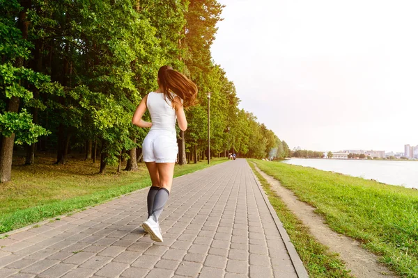 Beautiful female running on the bridge during everyday practice. Fitness woman jogging outdoors in park