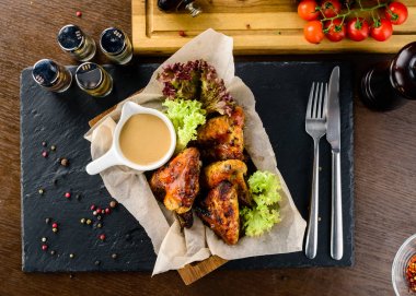 Rustik servis tahtasında kızarmış tavuk kanatları, ızgara tavuk kanatları servis