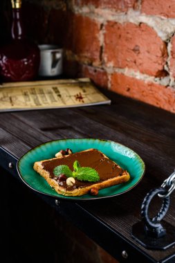 Tost ekmeği ile çikolata yayıldı ve çilek çilek yaban mersini nane bir ahşap stand tabloda gri.