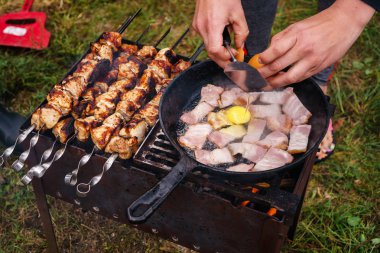 Turist kahvaltıda domuz pastırmalı yumurta hazırlıyor. Doğada demir bir tavada.