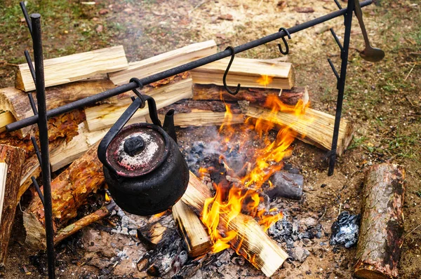 a teapot hangs on a fire, tea is heated for tourists