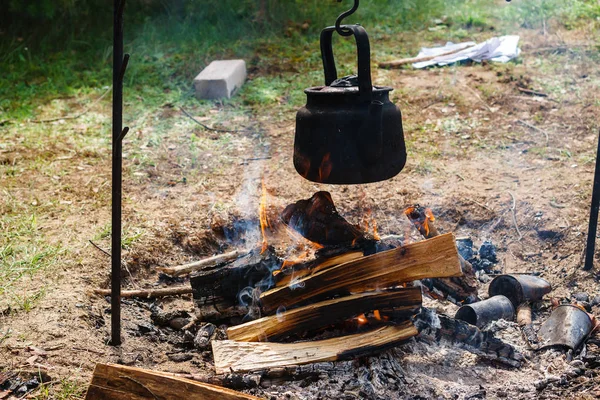 a teapot hangs on a fire, tea is heated for tourists