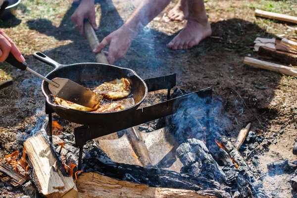 Cooking on a fire in the forest. on the grid are the pot and pan. in a frying pan fried pancakes