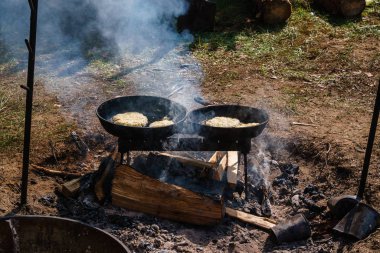 Patatesli gözleme, arka planda sıcak yağda kızartılmış. Kamp ateşinde yemek hazırlıyorum. Ukrayna mutfağı