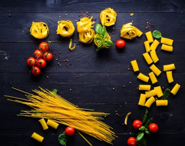 Makarna arka plan. Çeşitli sebze ve otlar ahşap bir masa üzerinde kuru makarna. Metin için özgür yer. Üstten Görünüm