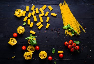 Makarna arka plan. Çeşitli sebze ve otlar ahşap bir masa üzerinde kuru makarna. Metin için özgür yer. Üstten Görünüm