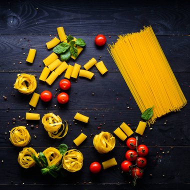 Makarna arka plan. Çeşitli sebze ve otlar ahşap bir masa üzerinde kuru makarna. Metin için özgür yer. Üstten Görünüm