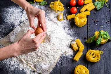 Aşçı kadın hamur için una yumurta kırıyor. Yumurta sarısını pişirmeye ekliyorum.