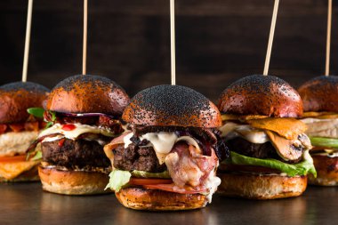 Farklı gurme hamburgerler, yanında balık köftesi, domuz pastırması ve kalamar. Düşük açılı ön manzara tavuğu, ahşap masada sığır burger. Kopyalama alanı içerir.