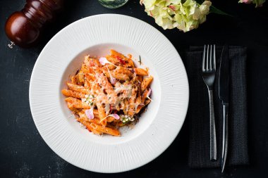 Bir tabak domates soslu makarna. Peynirli makarna, üstü açık, düz uzanmış.