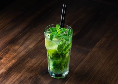 Buz küpü, kireç, ahşap zemin üzerinde nane yaprakları olan yüksek top bardakta naneli mojito kokteyli. Boşluğu kopyala