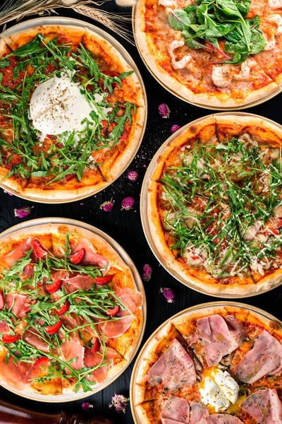 five different pizza set for menu on the wooden table. Italian food traditional cuisine. Pizzas with seafood, ham, bacon and vegetarian, top view, flat lay