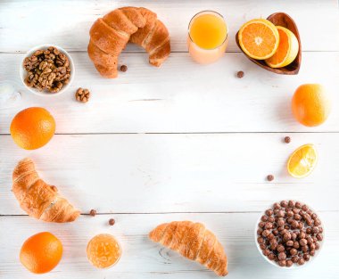 Tahta masa, kruvasan, portakal suyu ve mısır gevreği üzerine sağlıklı kahvaltı malzemeleri.