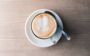 Ahşap bir masada latte, kahve kapuçino ve bir desen.