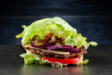 Salata ve biftekli düşük karbonhidratlı burger, ev yapımı tavşansız sığır eti yağsız hamburger marullu dürüm, paleo diyetindekiler için düşük karbonhidratlı ve domates ve soğanlı.