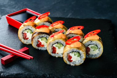 Geleneksel Japon mutfağı. Koyu arkaplanda krem peynirli suşi, pilav, kırmızı biber, patlıcanlı baharatlı suşi ve kırmızı biber.