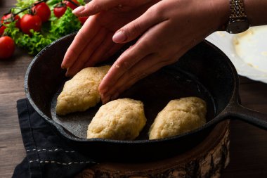 Kadın elleri tavada kızartmak için pirzola yontuyor, yakın plan kadın eli kızartma tavasında pirzola pişiriyor.