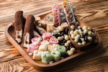 Doğulu tatlılar, fındıklar ve kuru meyveler, fındıklı ve şekerli şeker seti ahşap arka planda bir tepside