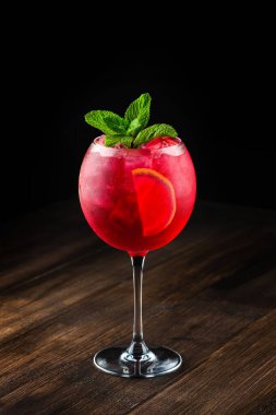 Ahşap bir arka planda kırmızı sangria. Geleneksel alkollü içecek, kırmızı şarap, meyve ve buzlu ahşap arka planda. Yakın plan kırmızı kokteyl, eski bir tahta üzerinde nane ve buz.