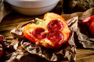 Kırmızı biberle pişirilmiş peynirli salam, tarifi salam dilimleri, kırmızı çan biberi ve erimiş peynirle kaplı fırında çıtır çıtır fırın.