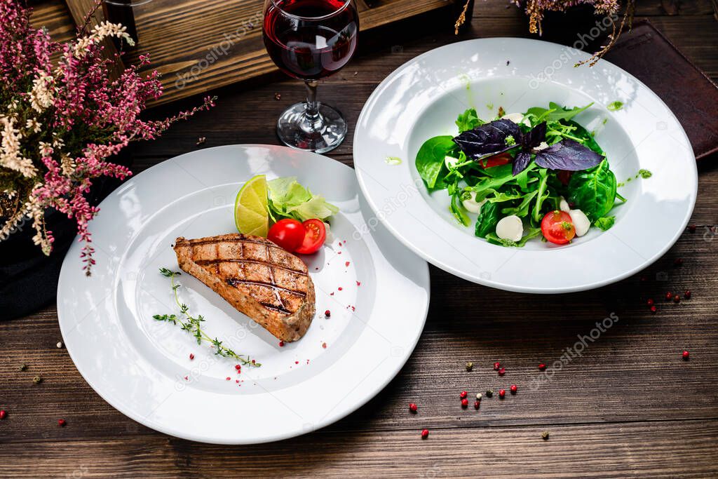 two plates of steak and salad on the table, lunch in the restaurant, grilled tuna